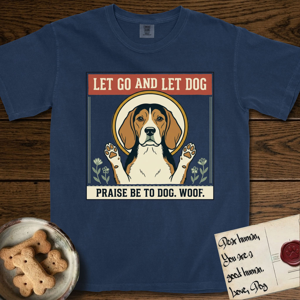 Let Go and Let Dog Beagle T-Shirt flat lay in True Navy, featuring a vintage seed packet label with a haloed tricolor Beagle, paws raised, flanked by simple flower sprigs.