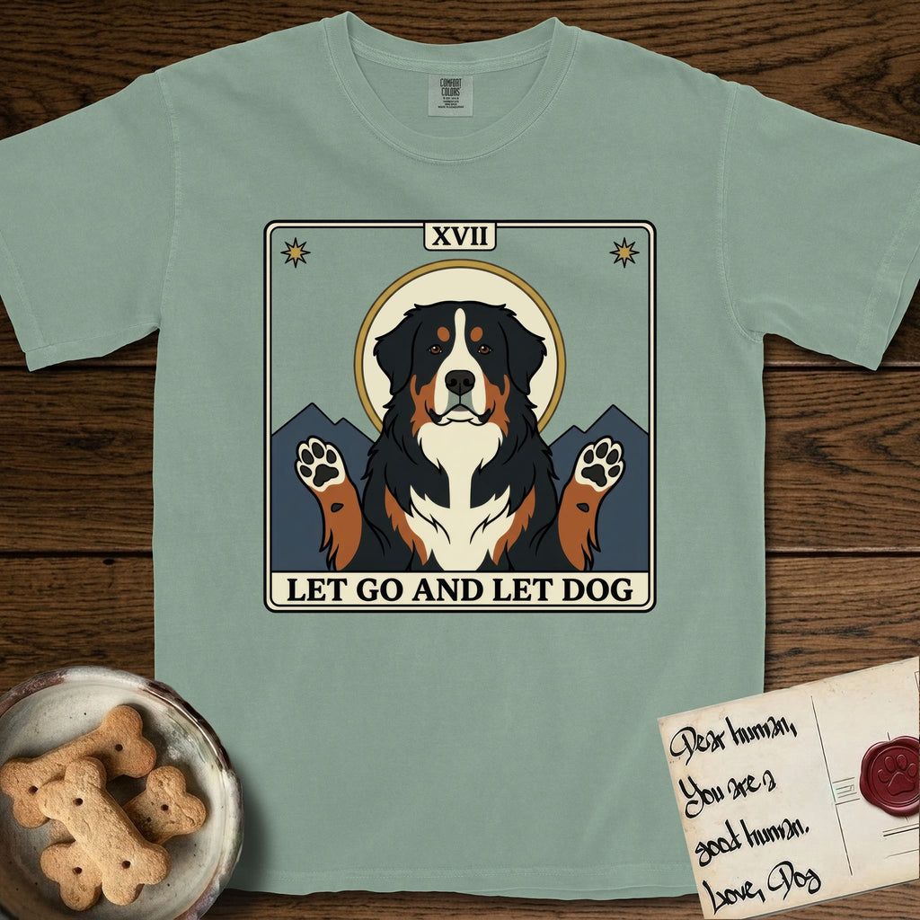 Let Go and Let Dog Bernese Mountain Dog T-Shirt flat lay in Bay, featuring a vintage tarot card with a haloed tricolor Bernese Mountain Dog, paws raised, mountains rising behind her shoulders.