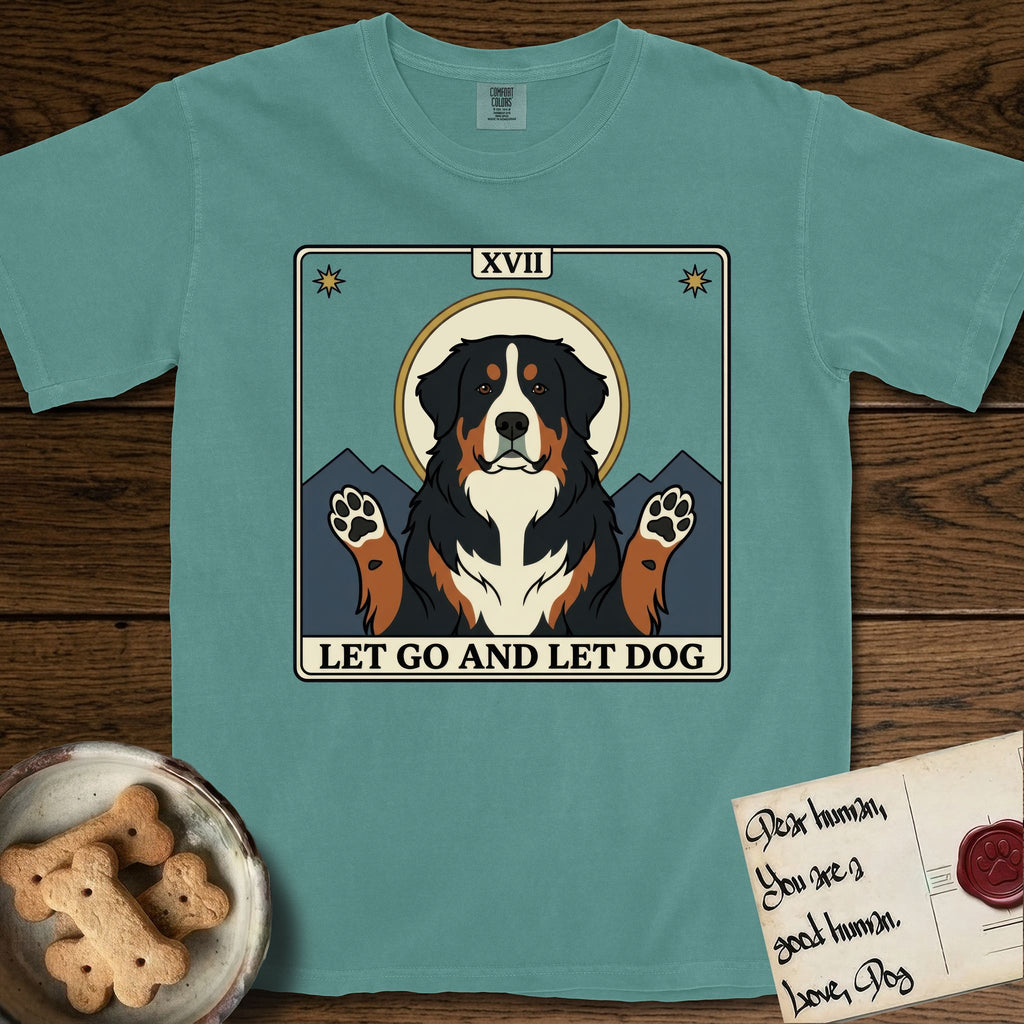 Let Go and Let Dog Bernese Mountain Dog T-Shirt flat lay in Blue Spruce, featuring a vintage tarot card with a haloed tricolor Bernese Mountain Dog, paws raised, mountains rising behind her shoulders.