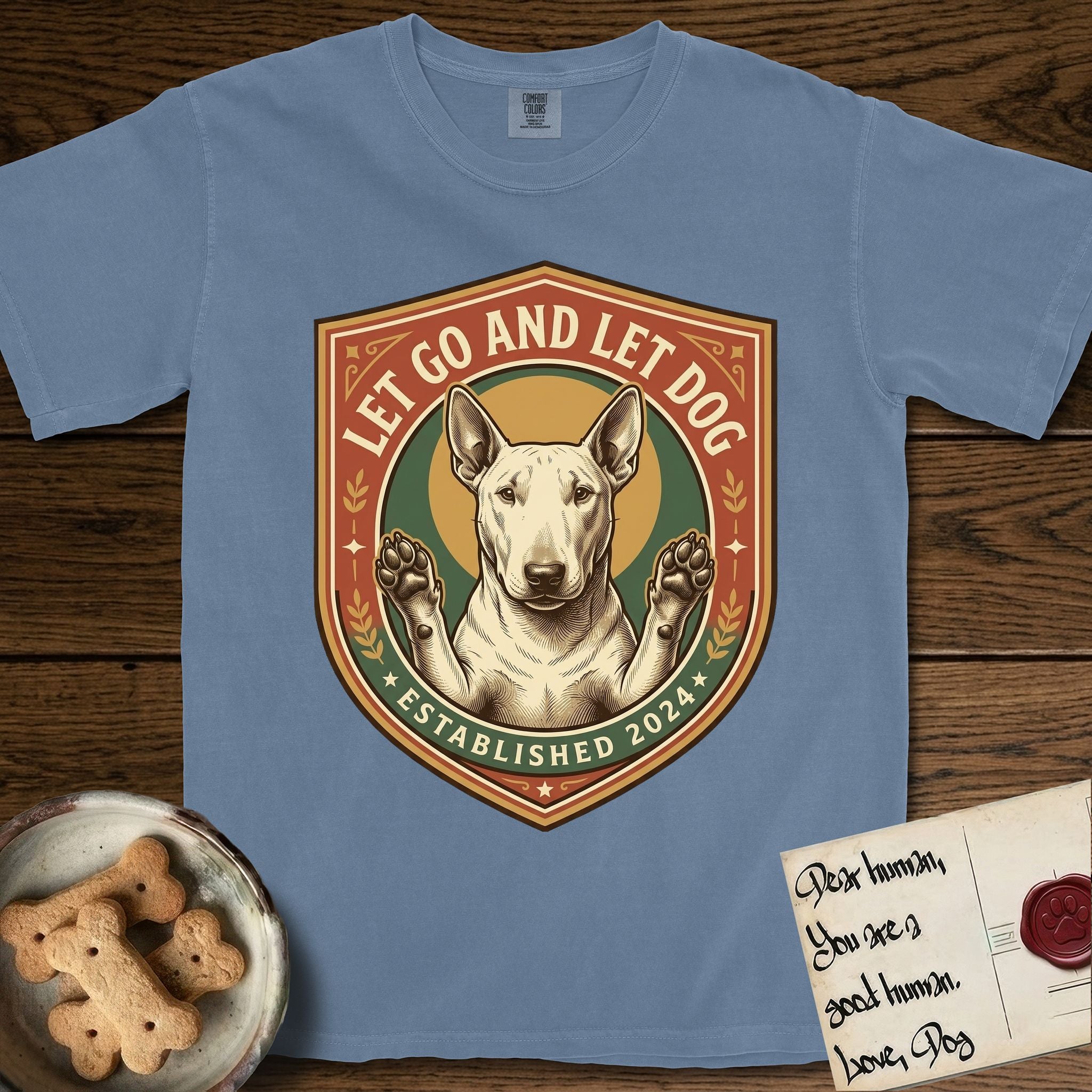 Let Go and Let Dog Bull Terrier T-Shirt flat lay in Blue Jean, featuring a vintage badge of a haloed Bull Terrier with paws raised in blessing.