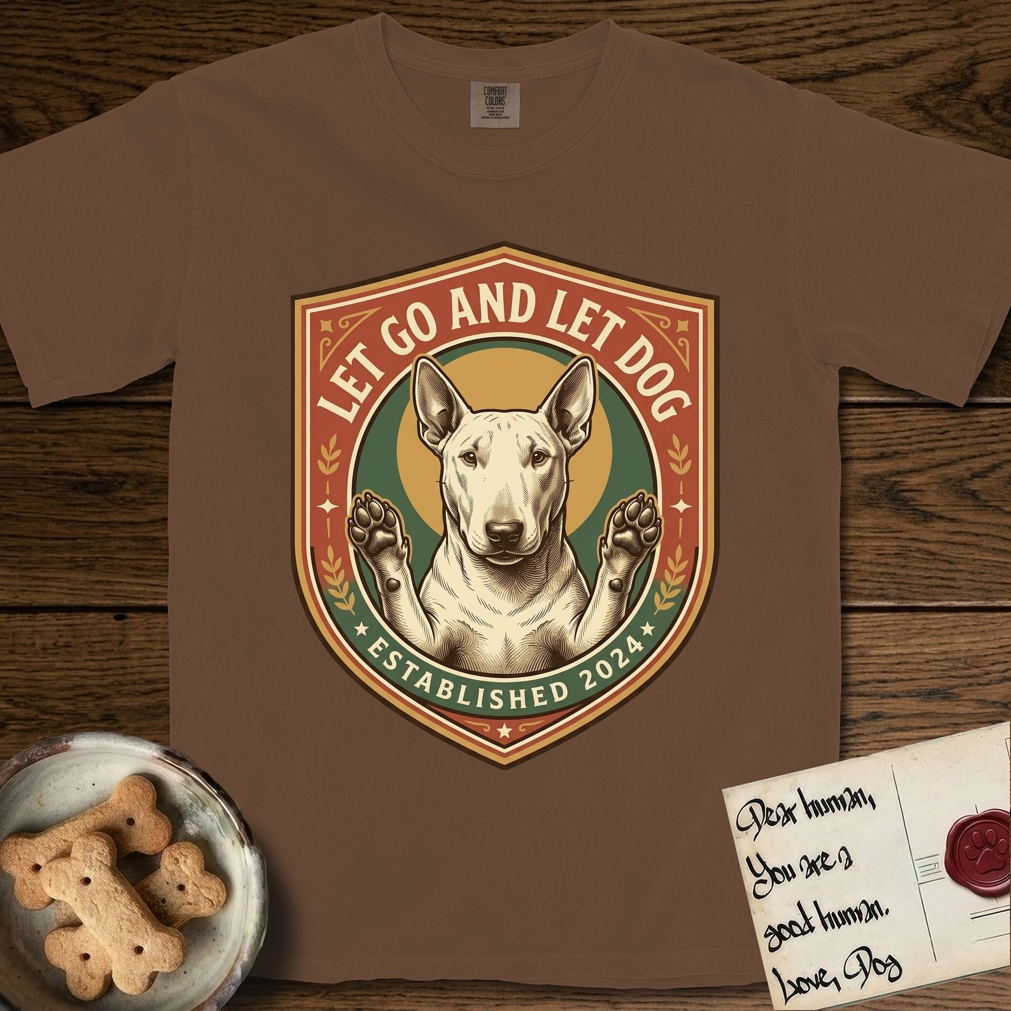 Let Go and Let Dog Bull Terrier T-Shirt flat lay in Espresso, featuring a vintage badge of a haloed Bull Terrier with paws raised in blessing.