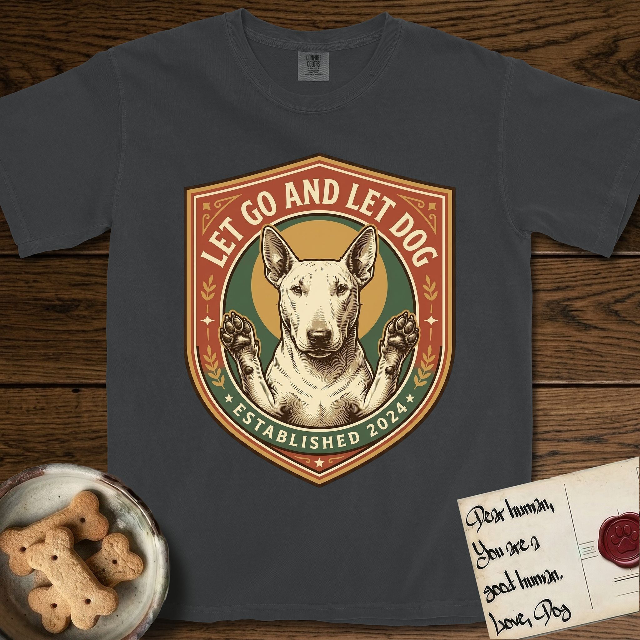 Let Go and Let Dog Bull Terrier T-Shirt flat lay in Graphite, featuring a vintage badge of a haloed Bull Terrier with paws raised in blessing.