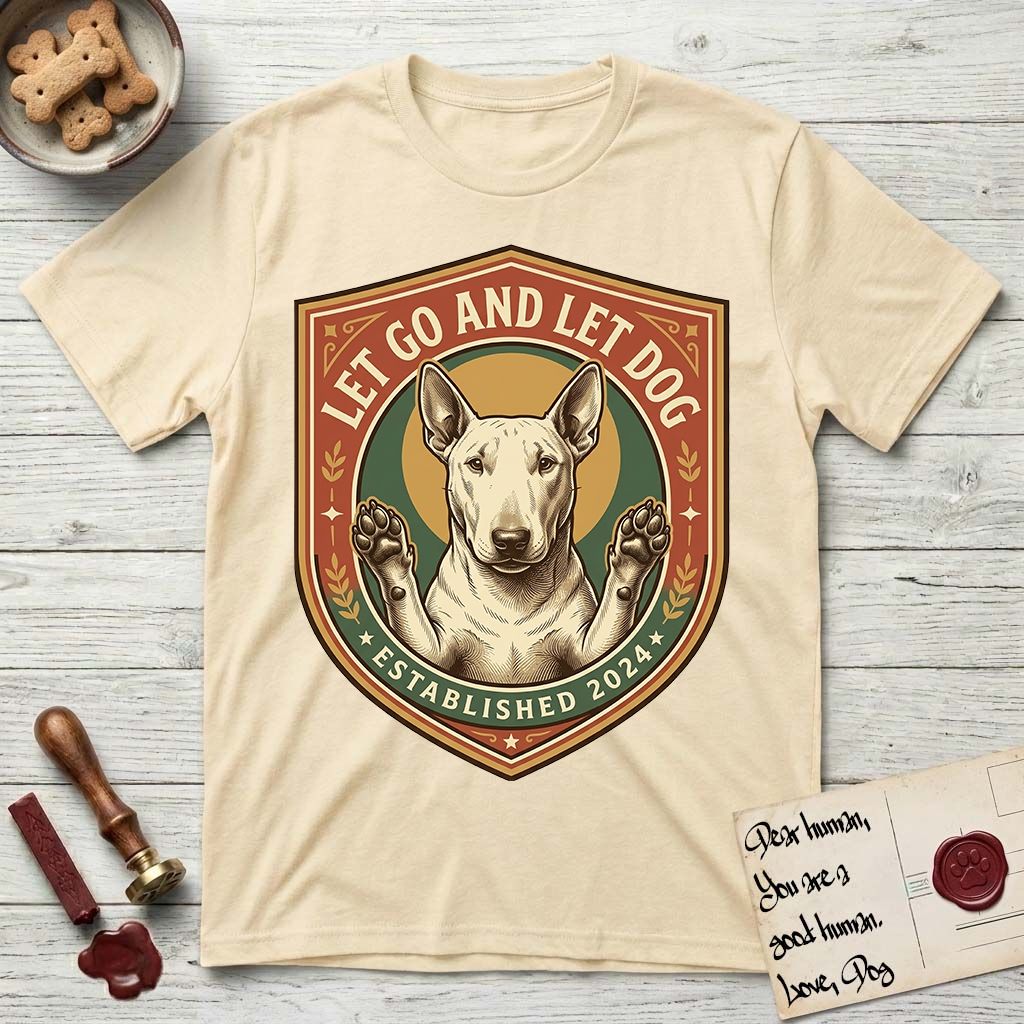 Let Go and Let Dog Bull Terrier T-Shirt flat lay in Natural, featuring a vintage badge of a haloed Bull Terrier with paws raised in blessing.
