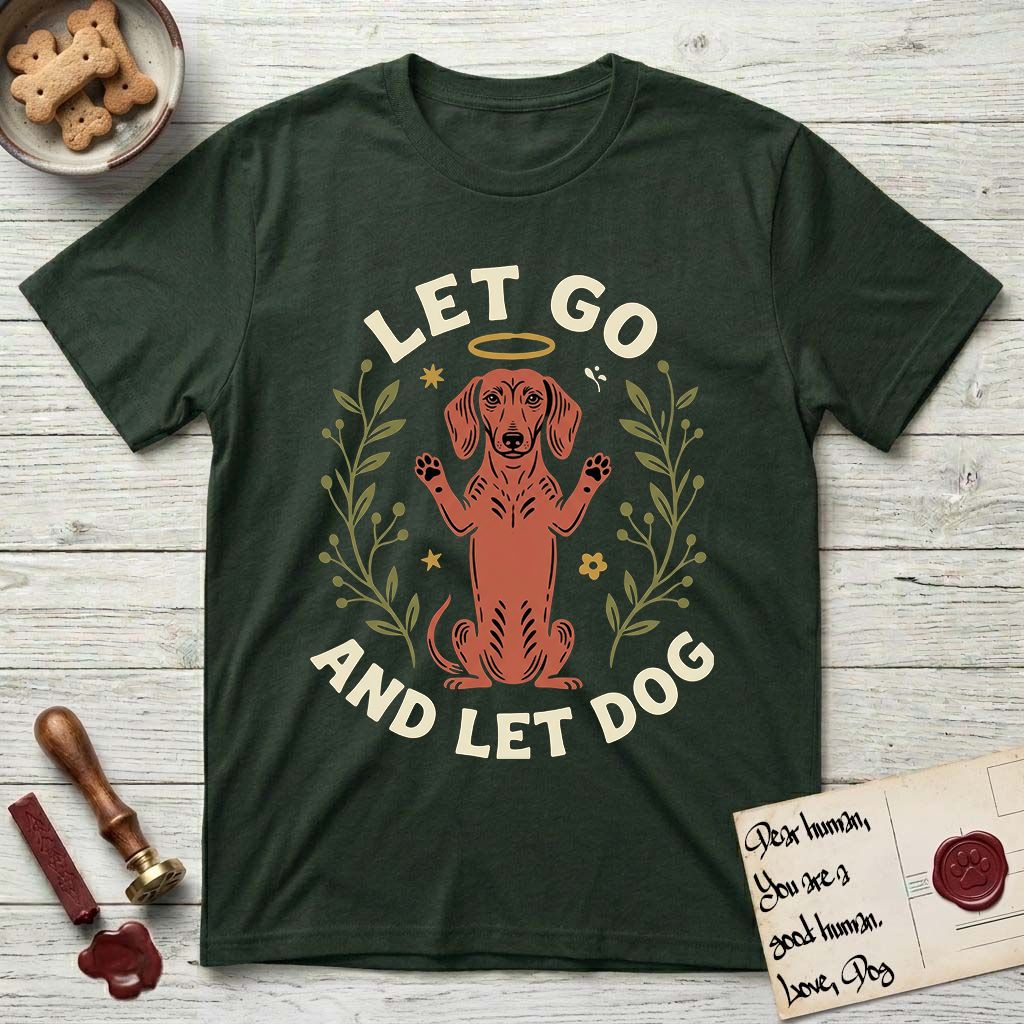 Let Go and Let Dog Dachshund T-Shirt flat lay in Forest Green, featuring a folk-art botanical illustration of a haloed Dachshund sitting up with front paws raised.