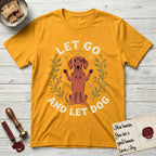 Let Go and Let Dog Dachshund T-Shirt flat lay in Gold, featuring a folk-art botanical illustration of a haloed Dachshund sitting up with front paws raised.