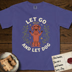 Let Go and Let Dog Dachshund T-Shirt flat lay in Grape, featuring a folk-art botanical illustration of a haloed Dachshund sitting up with front paws raised.