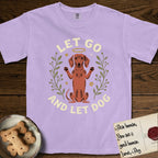 Let Go and Let Dog Dachshund T-Shirt flat lay in Orchid, featuring a folk-art botanical illustration of a haloed Dachshund sitting up with front paws raised.