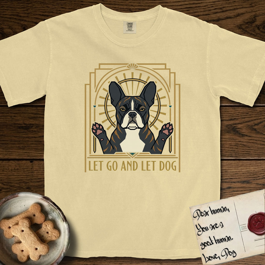 Let Go and Let Dog French Bulldog T-Shirt flat lay in Butter, featuring an Art Deco arch with a haloed brindle French Bulldog, bat ears erect and paws raised, gold sunburst rays behind him.