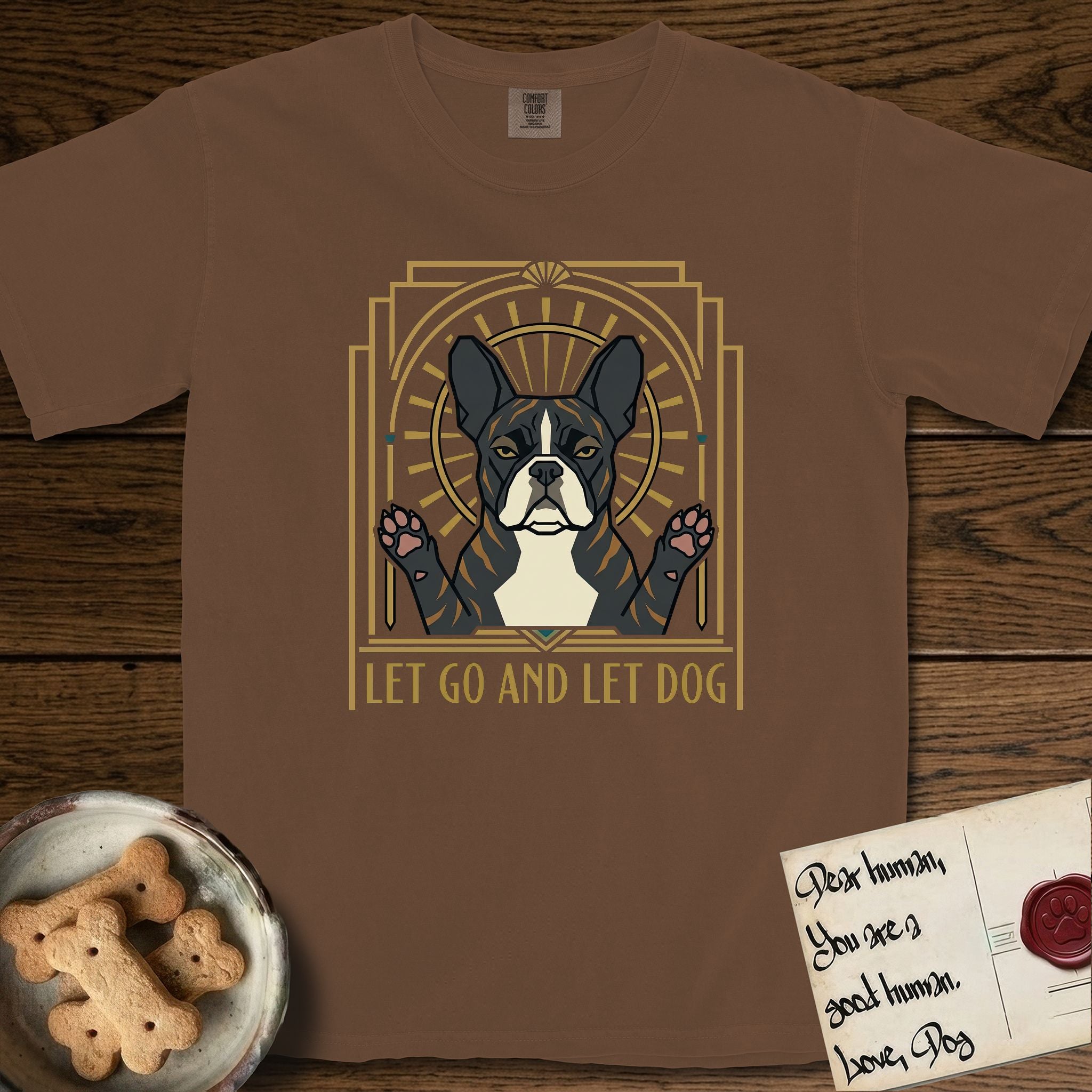 Let Go and Let Dog French Bulldog T-Shirt flat lay in Espresso, featuring an Art Deco arch with a haloed brindle French Bulldog, bat ears erect and paws raised, gold sunburst rays behind him.