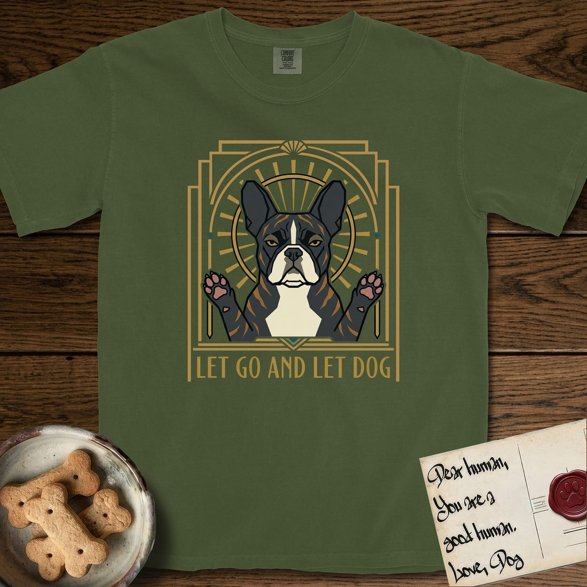 Let Go and Let Dog French Bulldog T-Shirt flat lay in Hemp, featuring an Art Deco arch with a haloed brindle French Bulldog, bat ears erect and paws raised, gold sunburst rays behind him.