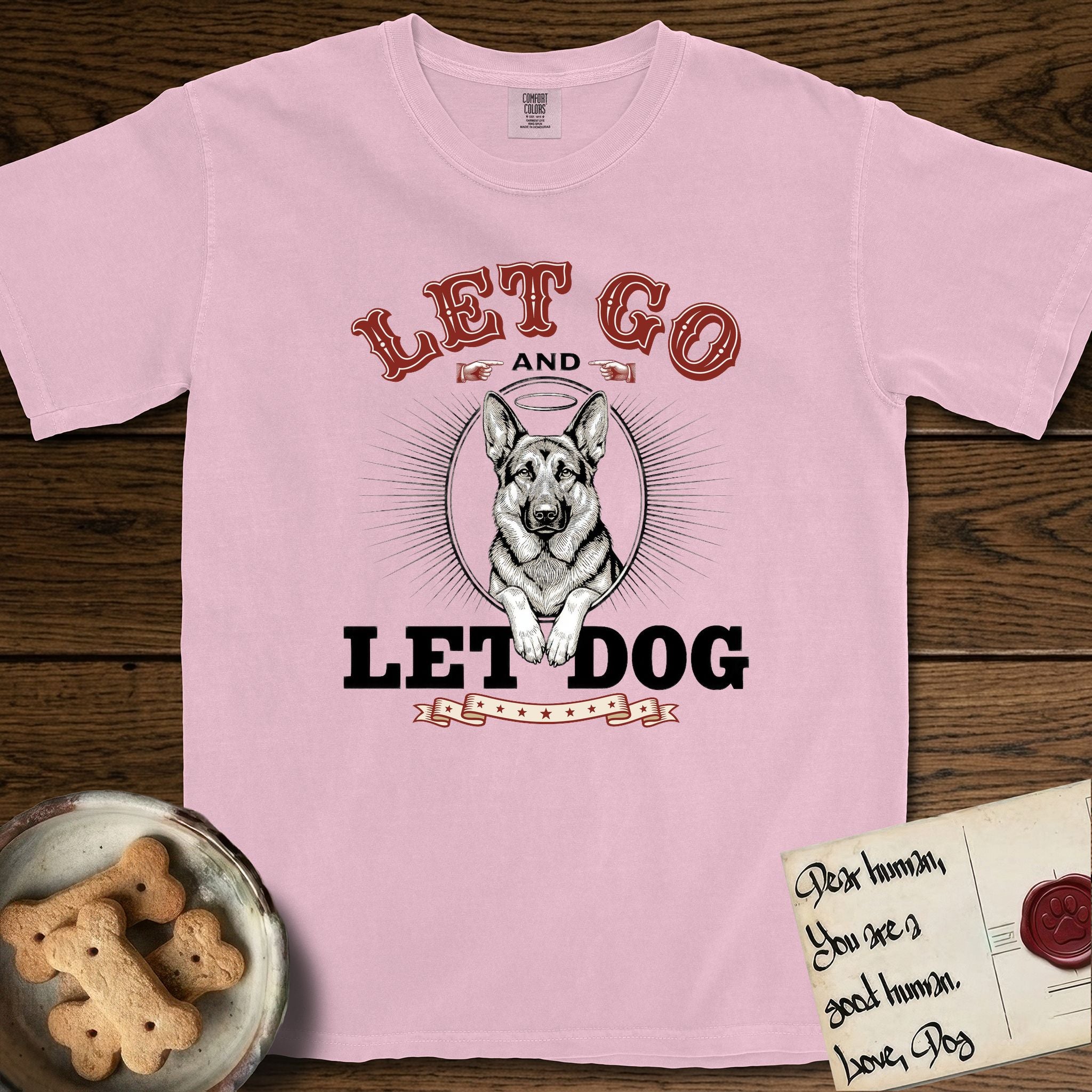 Let Go and Let Dog German Shepherd T-Shirt flat lay in Blossom, featuring a vintage letterpress engraving of a haloed German Shepherd framed by a sunburst oval.
