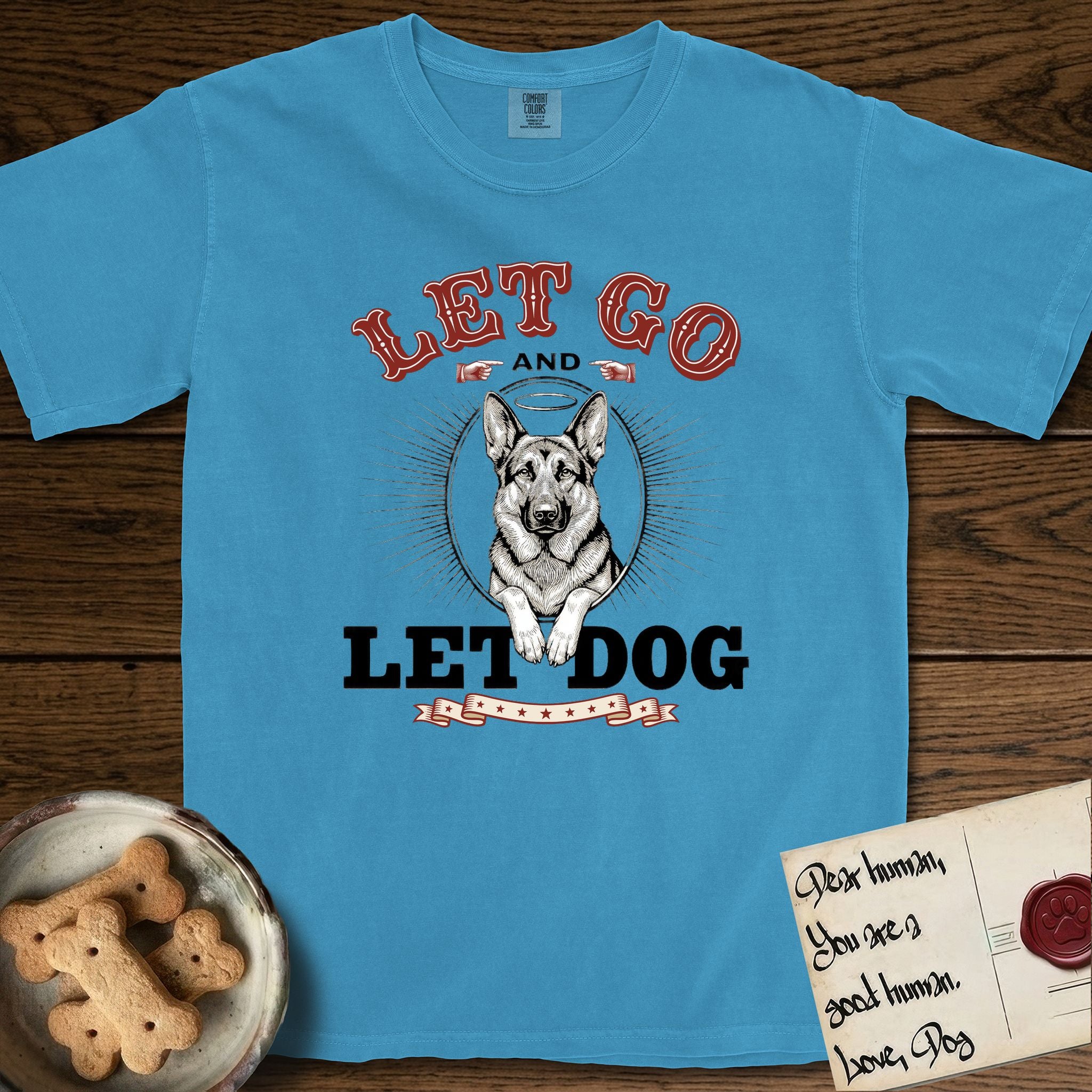 Let Go and Let Dog German Shepherd T-Shirt flat lay in Royal Caribe, featuring a vintage letterpress engraving of a haloed German Shepherd framed by a sunburst oval.