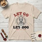 Let Go and Let Dog German Shepherd T-Shirt flat lay in Sand, featuring a vintage letterpress engraving of a haloed German Shepherd framed by a sunburst oval.