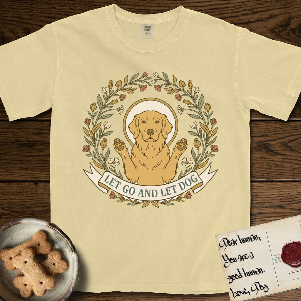 Let Go and Let Dog Golden Retriever T-Shirt flat lay in Butter, featuring an Art Nouveau wildflower wreath around a haloed Golden Retriever with front paws raised.