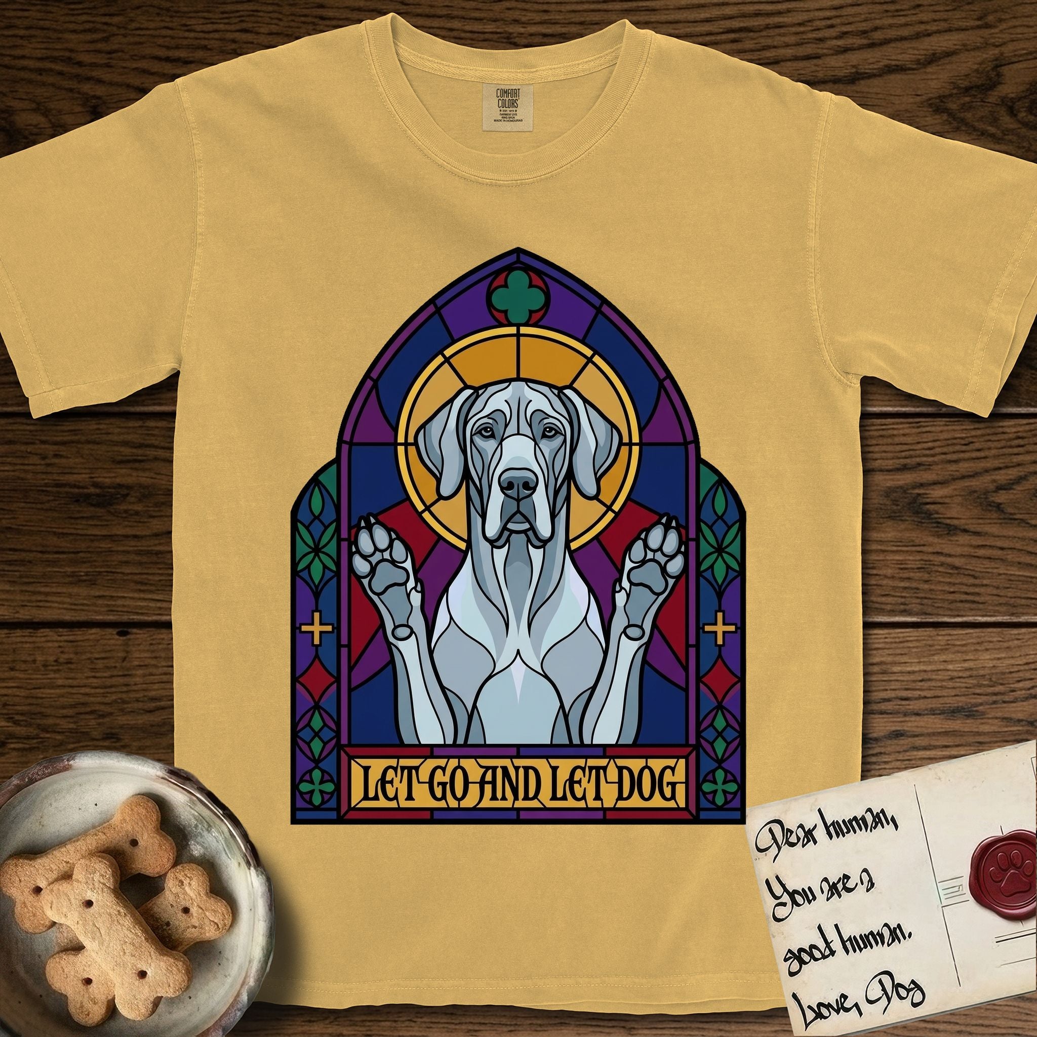 Let Go and Let Dog Great Dane T-Shirt flat lay in Mustard, featuring a stained-glass cathedral window of a haloed Great Dane with paws raised.