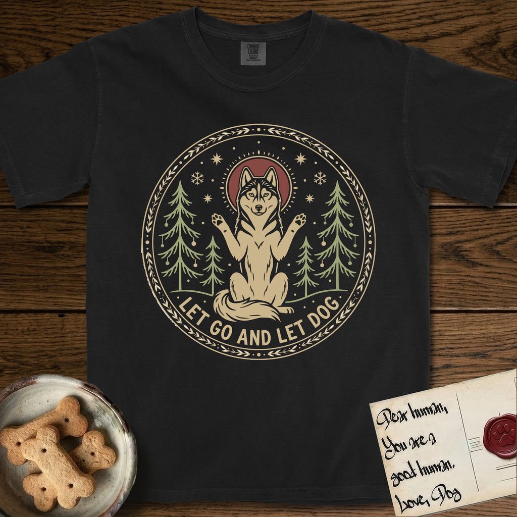 Let Go and Let Dog Husky T-Shirt flat lay in Black, featuring a winter woodland seal of a haloed Husky sitting with paws raised among pine trees.