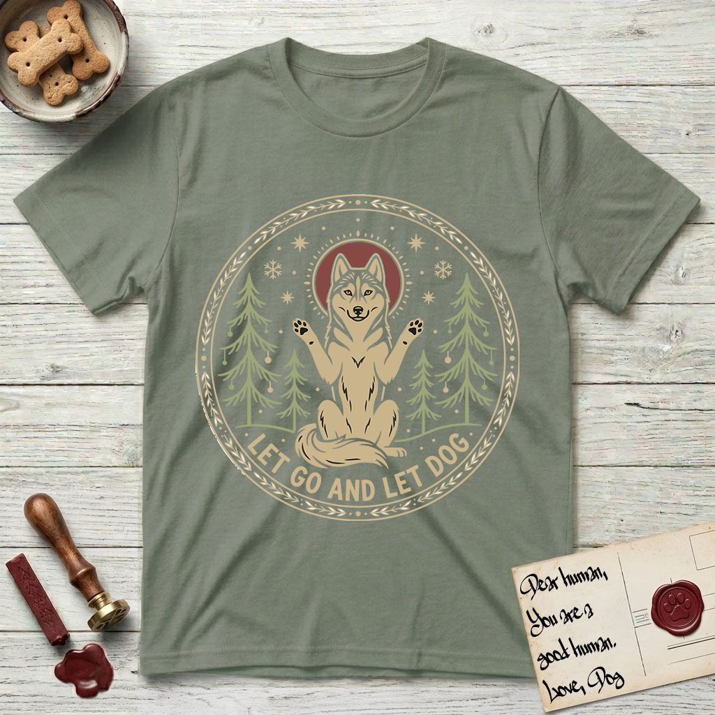 Let Go and Let Dog Husky T-Shirt flat lay in Sage, featuring a winter woodland seal of a haloed Husky sitting with paws raised among pine trees.