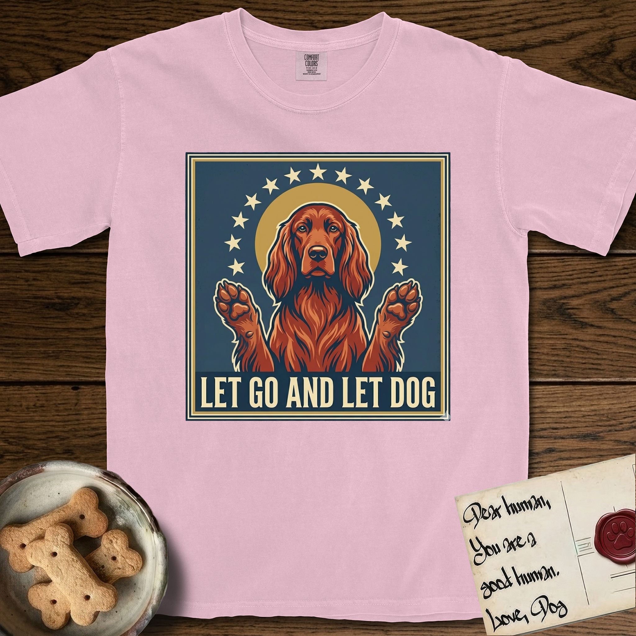 Let Go and Let Dog Irish Setter T-Shirt flat lay in Blossom, featuring a vintage devotional poster of a haloed Irish Setter with paws raised and a ring of stars.