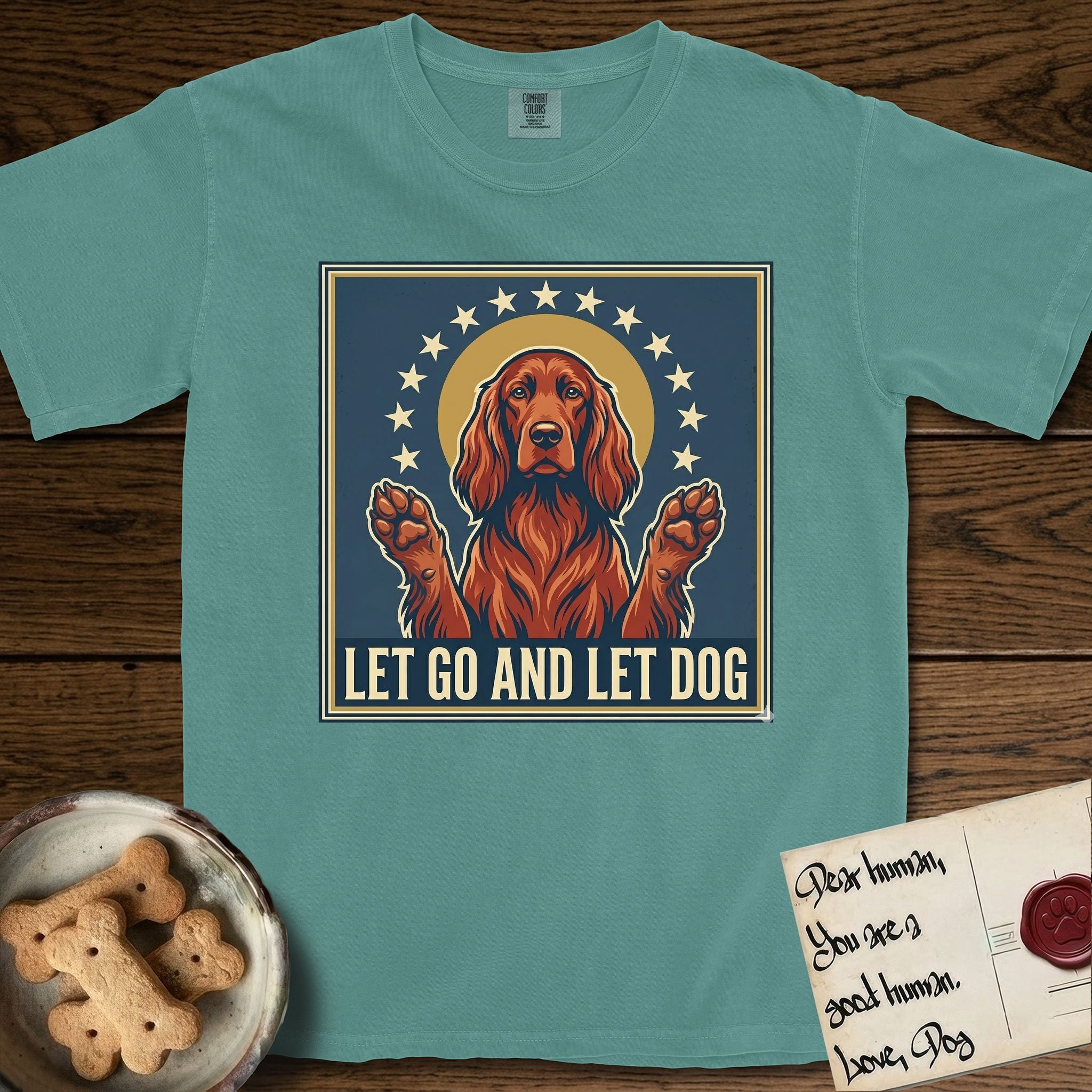 Let Go and Let Dog Irish Setter T-Shirt flat lay in Blue Spruce, featuring a vintage devotional poster of a haloed Irish Setter with paws raised and a ring of stars.