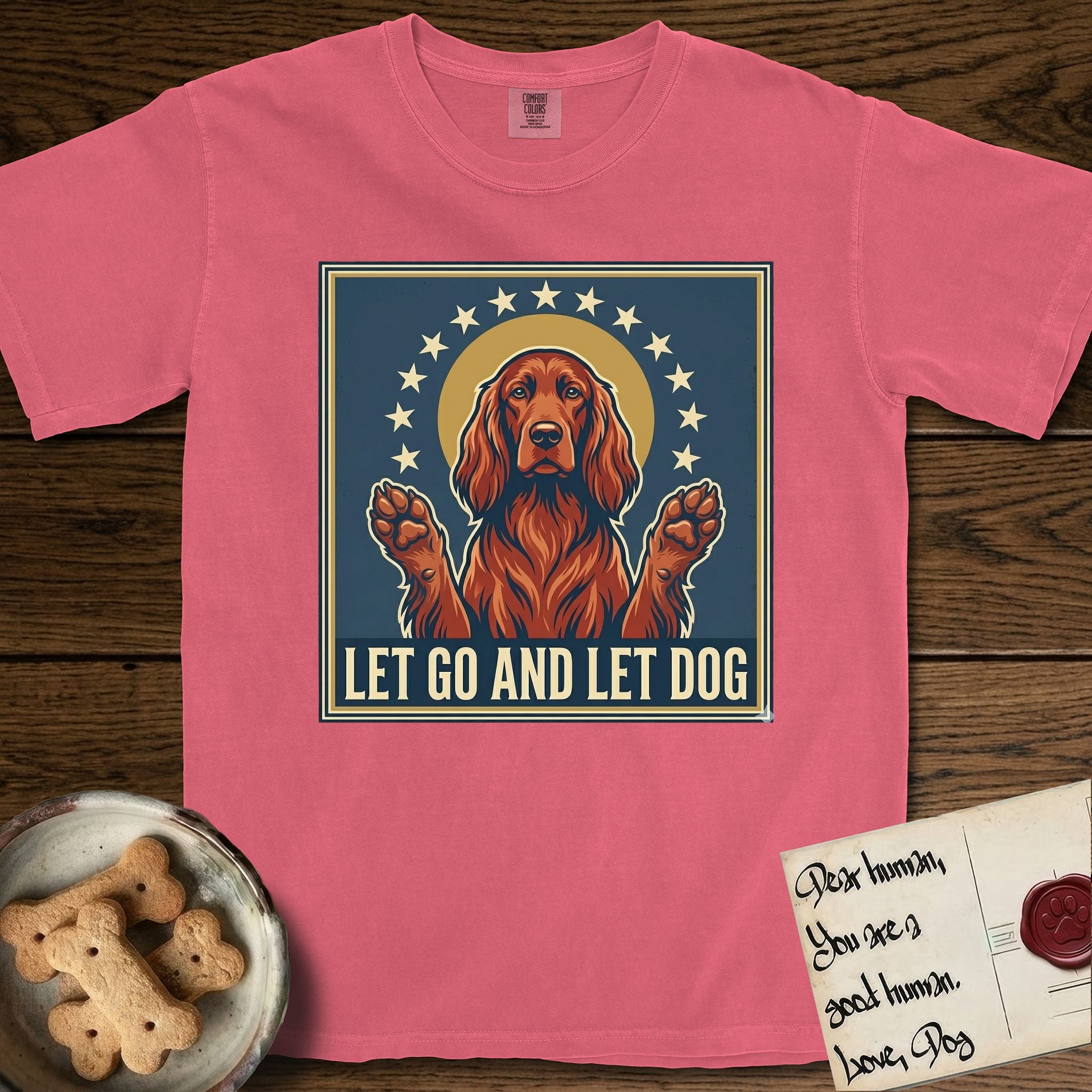 Let Go and Let Dog Irish Setter T-Shirt flat lay in Watermelon, featuring a vintage devotional poster of a haloed Irish Setter with paws raised and a ring of stars.