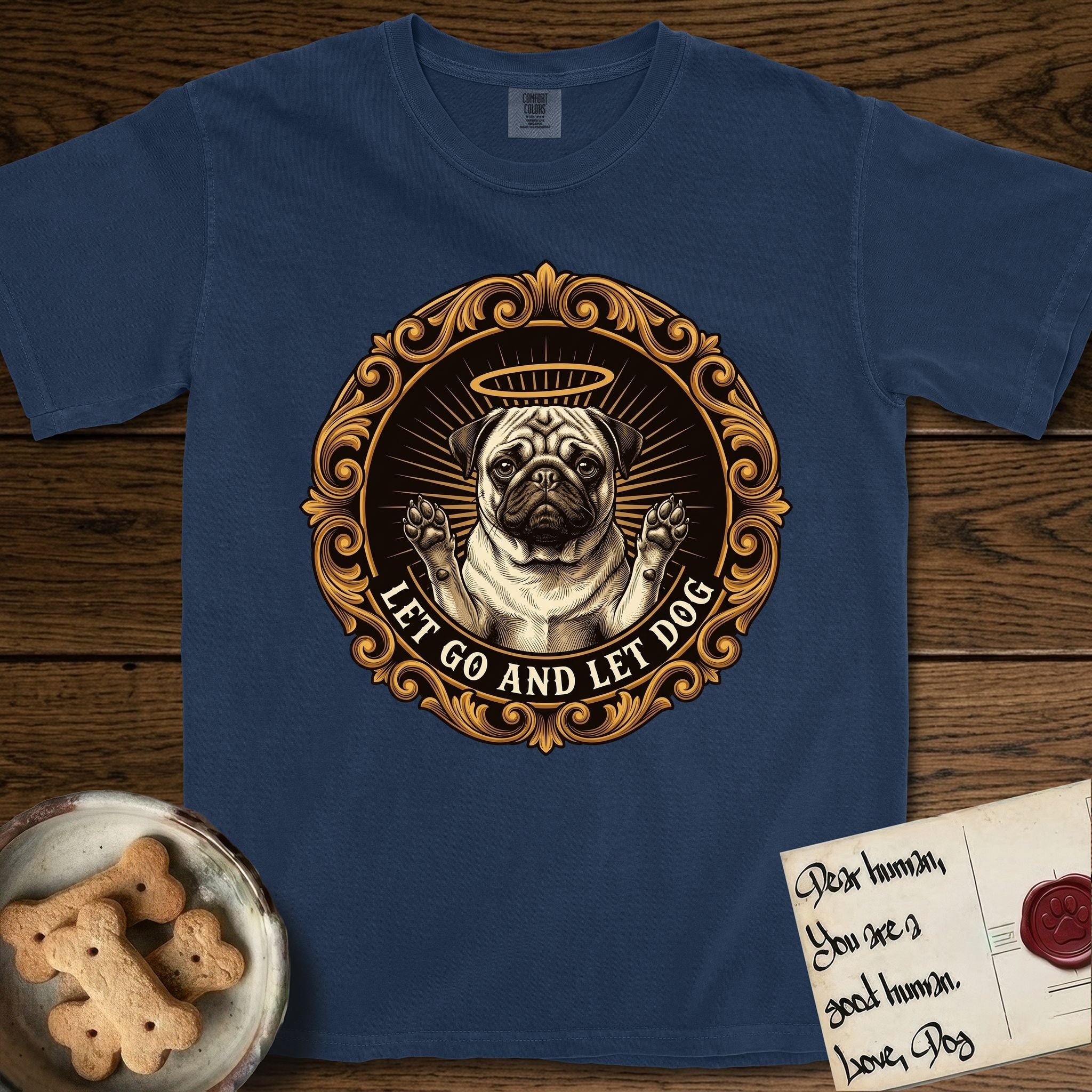 Let Go and Let Dog Pug T-Shirt flat lay in True Navy, featuring a baroque medallion engraving of a haloed Pug with paws raised, framed in gold scrollwork.