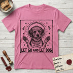 Let Go and Let Dog Rescue Mutt T-Shirt flat lay in Azalea, featuring a bold black-and-white woodcut of a haloed scruffy rescue mutt with both front paws raised.