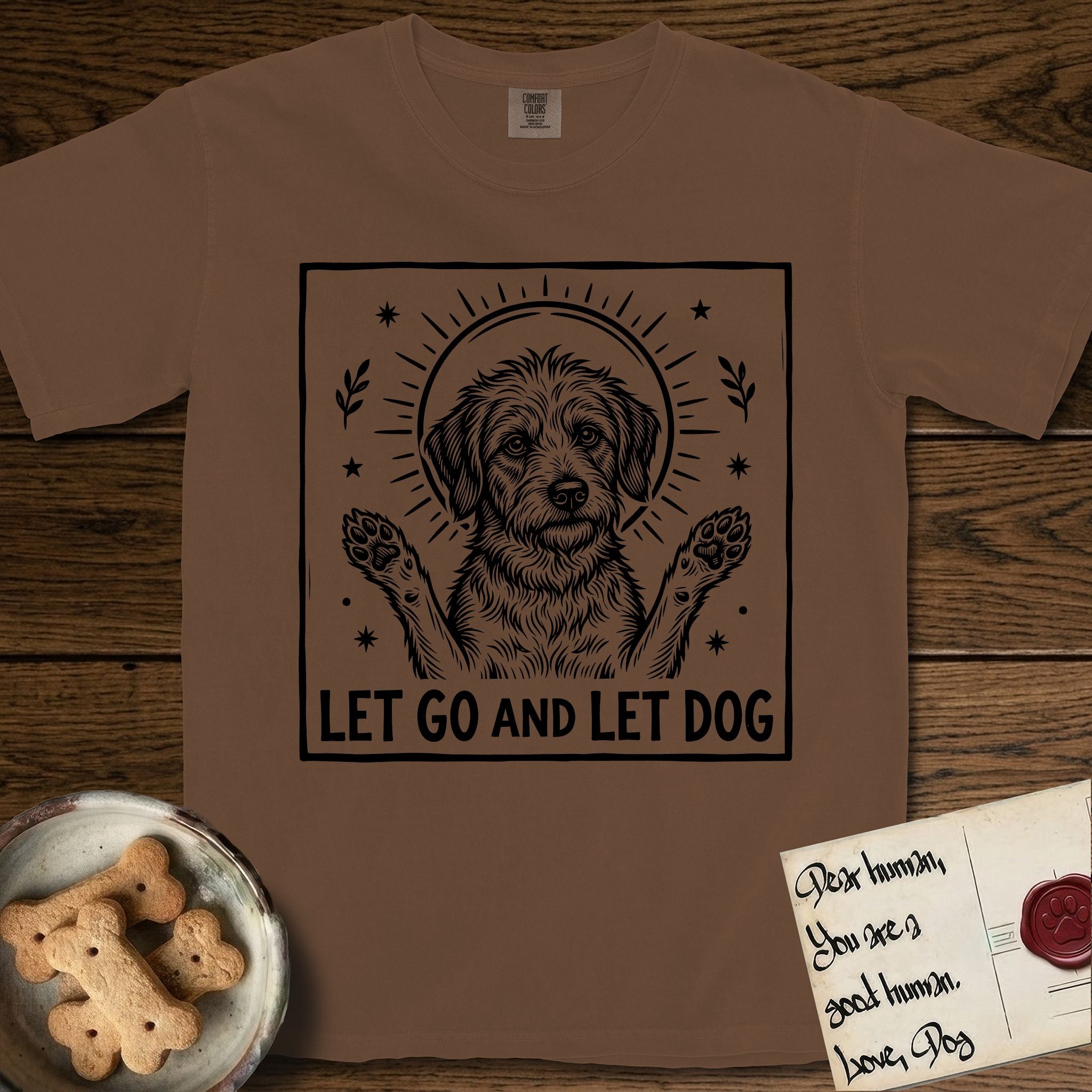Let Go and Let Dog Rescue Mutt T-Shirt flat lay in Espresso, featuring a bold black-and-white woodcut of a haloed scruffy rescue mutt with both front paws raised.