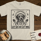 Let Go and Let Dog Rescue Mutt T-Shirt flat lay in Ivory, featuring a bold black-and-white woodcut of a haloed scruffy rescue mutt with both front paws raised.