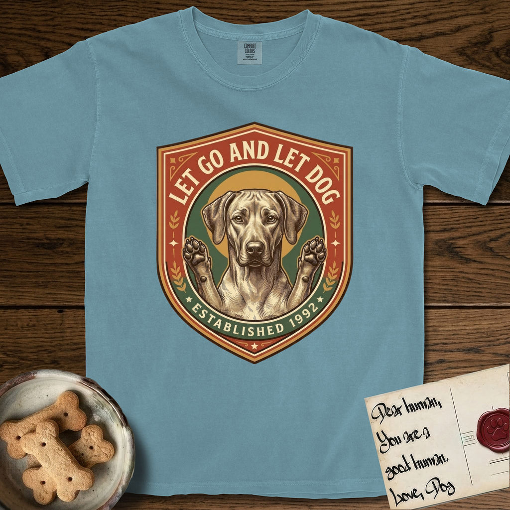 Let Go and Let Dog Rhodesian Ridgeback T-Shirt flat lay in Ice Blue, featuring a vintage engraved crest of a haloed Rhodesian Ridgeback with front paws raised.