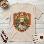 Let Go and Let Dog Rhodesian Ridgeback T-Shirt flat lay in Sand, featuring a vintage engraved crest of a haloed Rhodesian Ridgeback with front paws raised.
