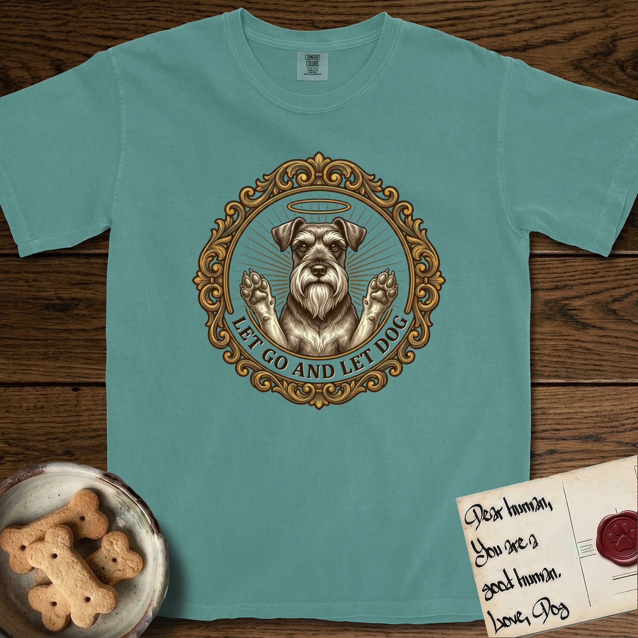 Let Go and Let Dog Schnauzer T-Shirt flat lay in Blue Spruce, featuring an ornate gilded medallion of a haloed Schnauzer with front paws raised.