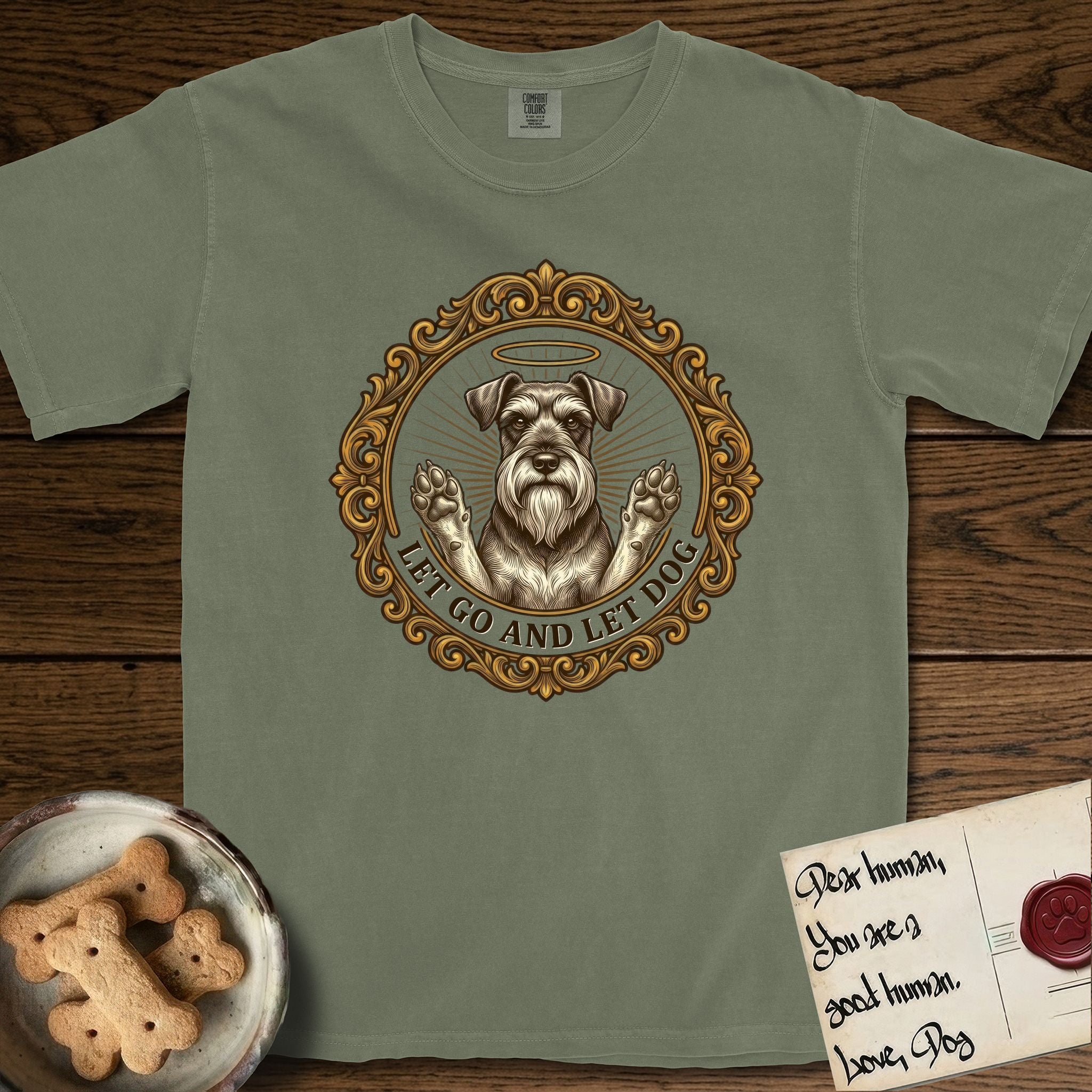 Let Go and Let Dog Schnauzer T-Shirt flat lay in Sage, featuring an ornate gilded medallion of a haloed Schnauzer with front paws raised.