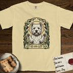 Let Go and Let Dog Westie T-Shirt flat lay in Butter, featuring an Art Nouveau arch of thistles and curling vines around a haloed West Highland White Terrier, paws raised.