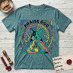 Praise Dog From Whom All Blessings Flow Australian Cattle Dog T-Shirt flat lay in Heather Galapagos Blue, featuring a neon pop-art illustration of an abstract Australian Cattle Dog with bold outlined "Praise Dog From Whom All Blessings Flow" lettering.