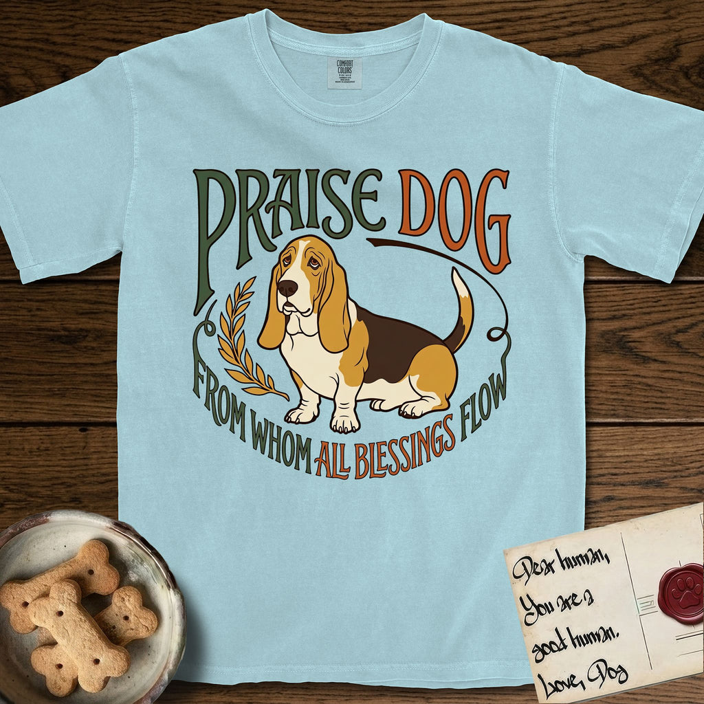 Praise Dog From Whom All Blessings Flow Basset Hound T-Shirt flat lay in Chambray, featuring an art nouveau hand-lettered design with a sad-eyed Basset Hound sitting beside a golden laurel sprig and the words Praise Dog From Whom All Blessings Flow.