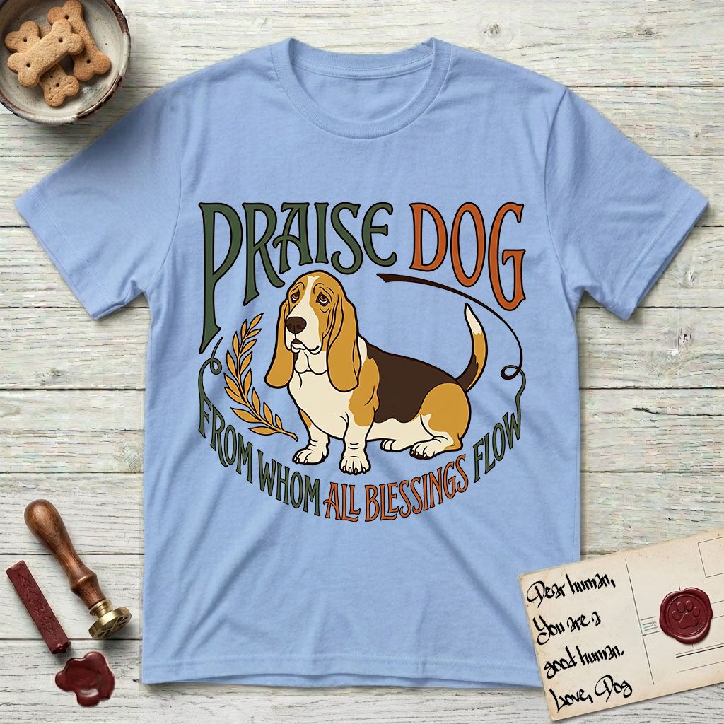 Praise Dog From Whom All Blessings Flow Basset Hound T-Shirt flat lay in Light Blue, featuring an art nouveau hand-lettered design with a sad-eyed Basset Hound sitting beside a golden laurel sprig and the words Praise Dog From Whom All Blessings Flow.