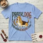 Praise Dog From Whom All Blessings Flow Basset Hound T-Shirt flat lay in Light Blue, featuring an art nouveau hand-lettered design with a sad-eyed Basset Hound sitting beside a golden laurel sprig and the words Praise Dog From Whom All Blessings Flow.