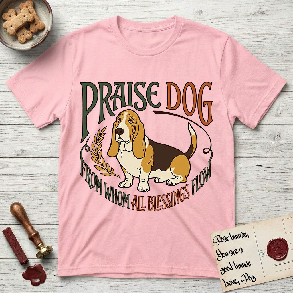 Praise Dog From Whom All Blessings Flow Basset Hound T-Shirt flat lay in Light Pink, featuring an art nouveau hand-lettered design with a sad-eyed Basset Hound sitting beside a golden laurel sprig and the words Praise Dog From Whom All Blessings Flow.