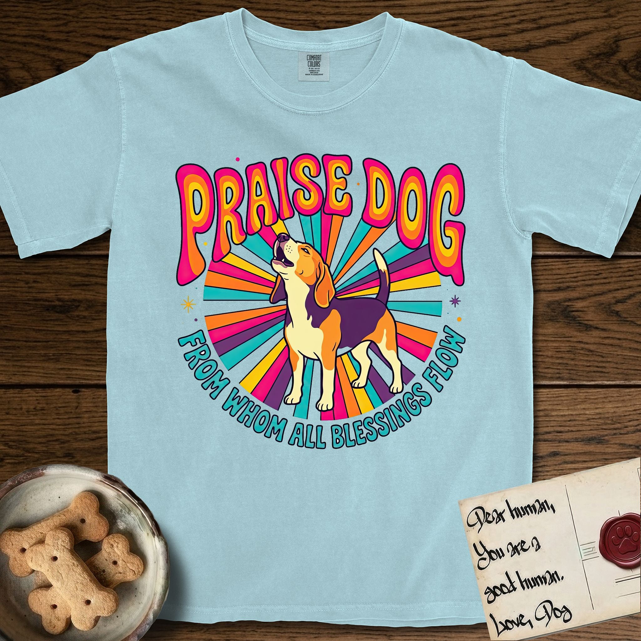 Praise Dog From Whom All Blessings Flow Beagle T-Shirt flat lay in Chambray, featuring a groovy psychedelic sunburst design with a Beagle howling skyward at the center and the words Praise Dog From Whom All Blessings Flow in rainbow bubble letters.