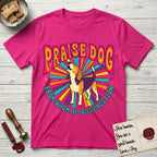 Praise Dog From Whom All Blessings Flow Beagle T-Shirt flat lay in Heliconia, featuring a groovy psychedelic sunburst design with a Beagle howling skyward at the center and the words Praise Dog From Whom All Blessings Flow in rainbow bubble letters.