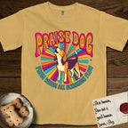 Praise Dog From Whom All Blessings Flow Beagle T-Shirt flat lay in Mustard, featuring a groovy psychedelic sunburst design with a Beagle howling skyward at the center and the words Praise Dog From Whom All Blessings Flow in rainbow bubble letters.