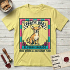 Praise Dog From Whom All Blessings Flow Chihuahua T-Shirt flat lay in Cornsilk, featuring a loteria-style folk art card with a Chihuahua seated inside a papel picado border, a banner reading El Perro Sagrado, and the words Praise Dog From Whom All Blessings Flow.