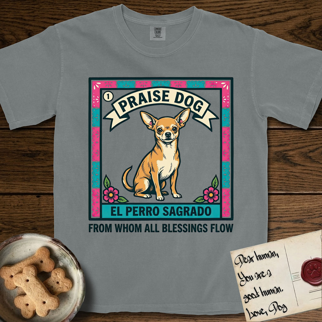 Praise Dog From Whom All Blessings Flow Chihuahua T-Shirt flat lay in Granite, featuring a loteria-style folk art card with a Chihuahua seated inside a papel picado border, a banner reading El Perro Sagrado, and the words Praise Dog From Whom All Blessings Flow.