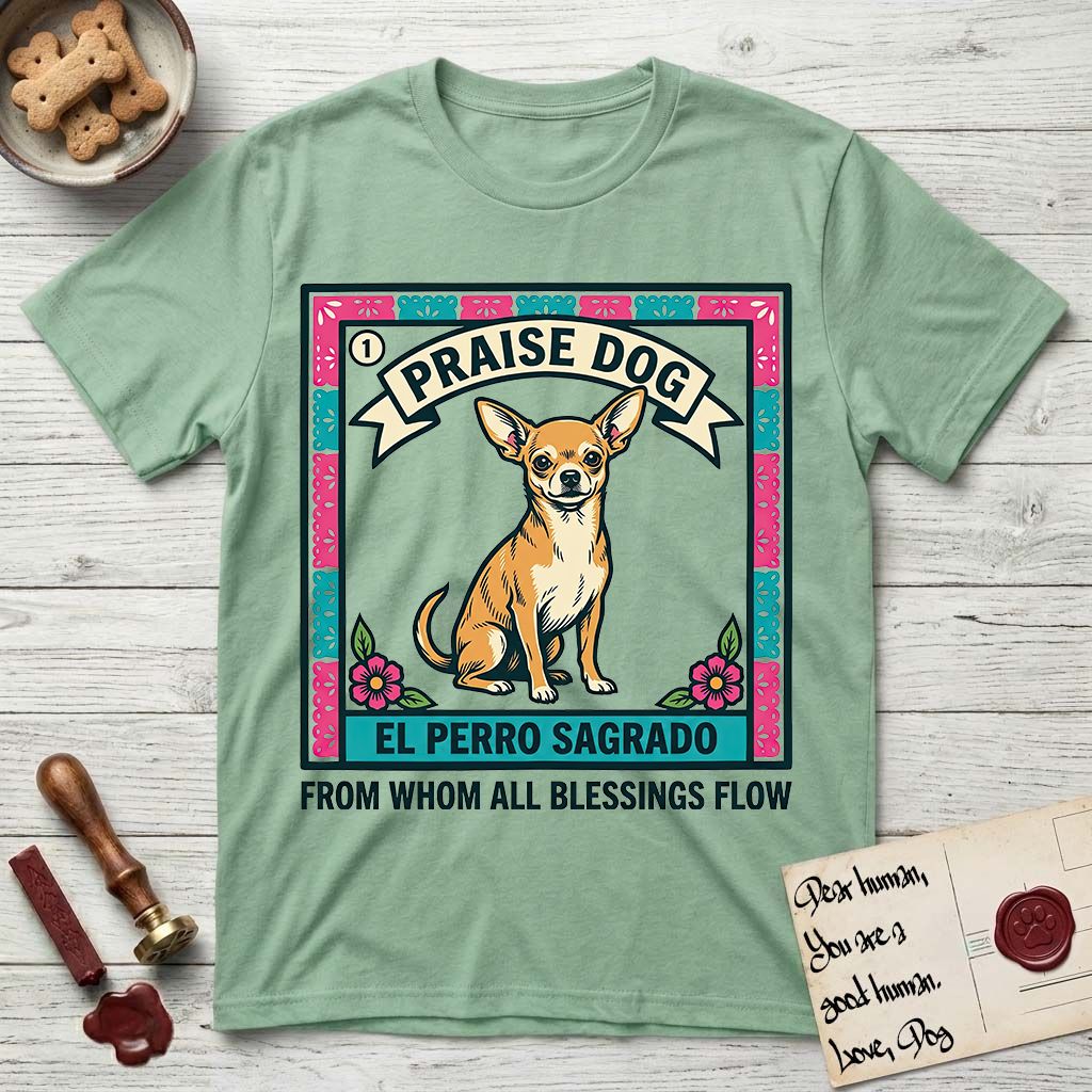 Praise Dog From Whom All Blessings Flow Chihuahua T-Shirt flat lay in Mint Green, featuring a loteria-style folk art card with a Chihuahua seated inside a papel picado border, a banner reading El Perro Sagrado, and the words Praise Dog From Whom All Blessings Flow.