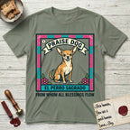 Praise Dog From Whom All Blessings Flow Chihuahua T-Shirt flat lay in Sage, featuring a loteria-style folk art card with a Chihuahua seated inside a papel picado border, a banner reading El Perro Sagrado, and the words Praise Dog From Whom All Blessings Flow.