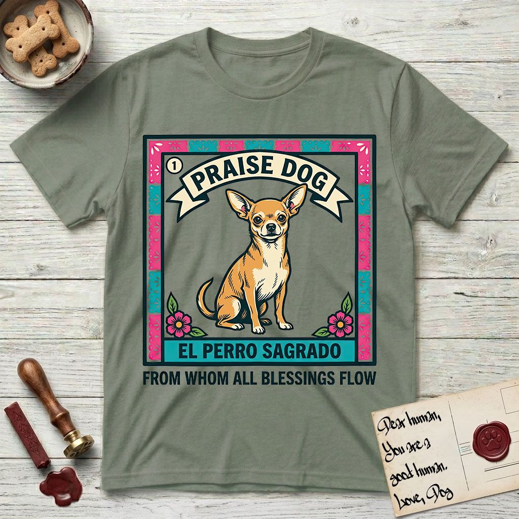 Praise Dog From Whom All Blessings Flow Chihuahua T-Shirt flat lay in Sage, featuring a loteria-style folk art card with a Chihuahua seated inside a papel picado border, a banner reading El Perro Sagrado, and the words Praise Dog From Whom All Blessings Flow.
