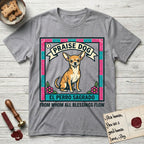 Praise Dog From Whom All Blessings Flow Chihuahua T-Shirt flat lay in Sport Grey, featuring a loteria-style folk art card with a Chihuahua seated inside a papel picado border, a banner reading El Perro Sagrado, and the words Praise Dog From Whom All Blessings Flow.