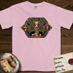 Praise Dog From Whom All Blessings Flow Corgi T-Shirt flat lay in Blossom, featuring a jeweled baroque throne emblem with a Corgi at center, a golden gemstone frame, raised golden hands in blessing, and the words Praise Dog.