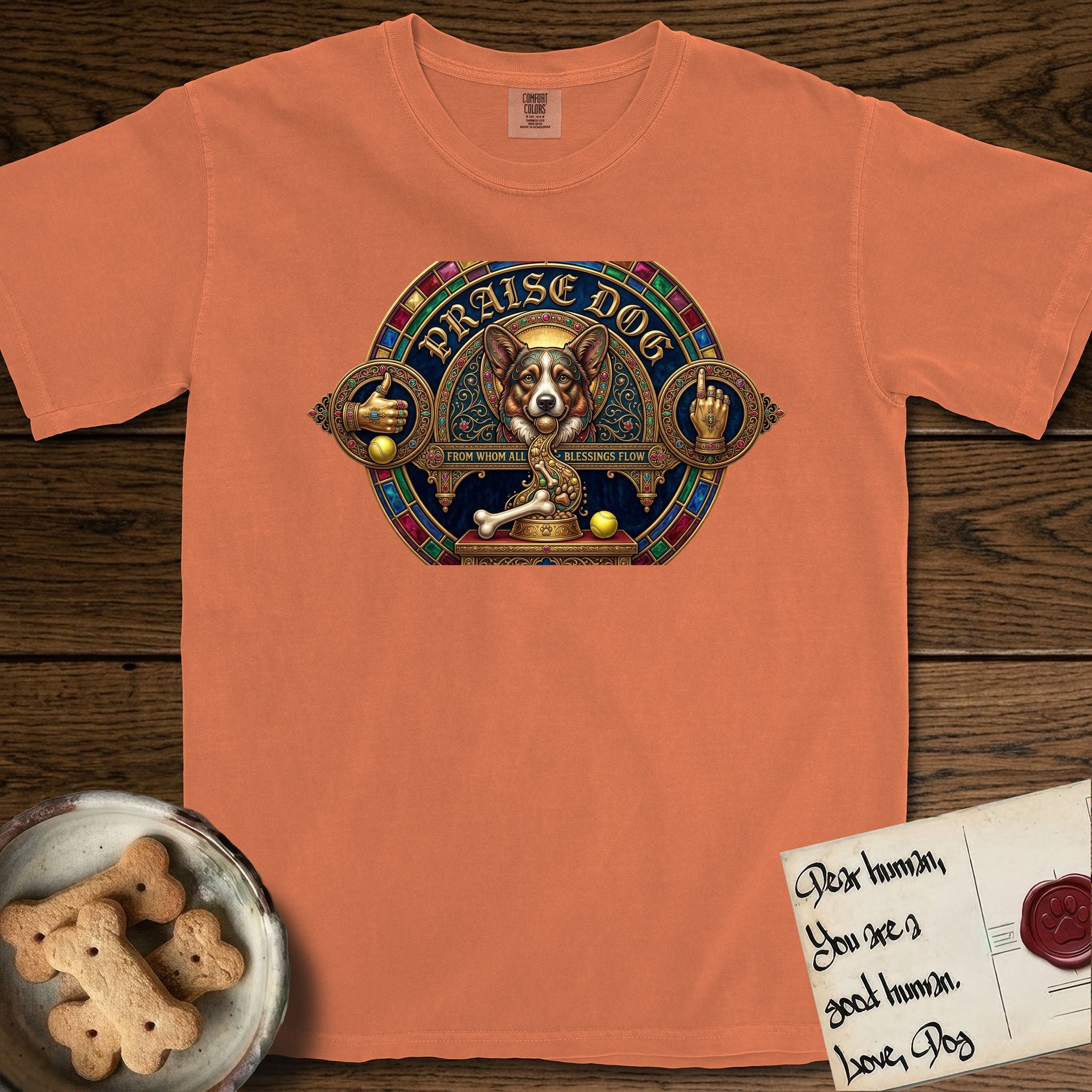Praise Dog From Whom All Blessings Flow Corgi T-Shirt flat lay in Melon, featuring a jeweled baroque throne emblem with a Corgi at center, a golden gemstone frame, raised golden hands in blessing, and the words Praise Dog.