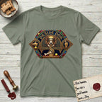 Praise Dog From Whom All Blessings Flow Corgi T-Shirt flat lay in Sage, featuring a jeweled baroque throne emblem with a Corgi at center, a golden gemstone frame, raised golden hands in blessing, and the words Praise Dog.